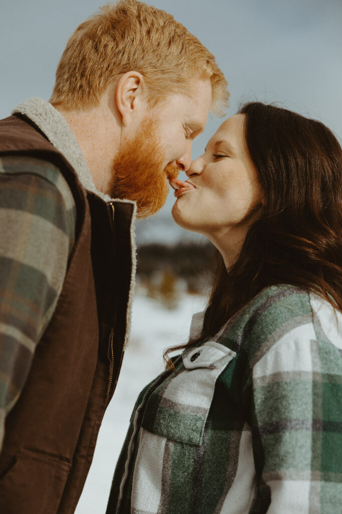 close up of couple touching tongues and being silly in the snow