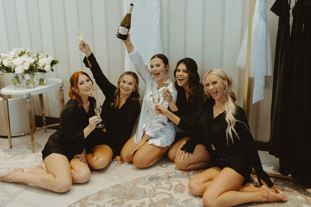 bride and bridesmaids cheering with champagne before wedding